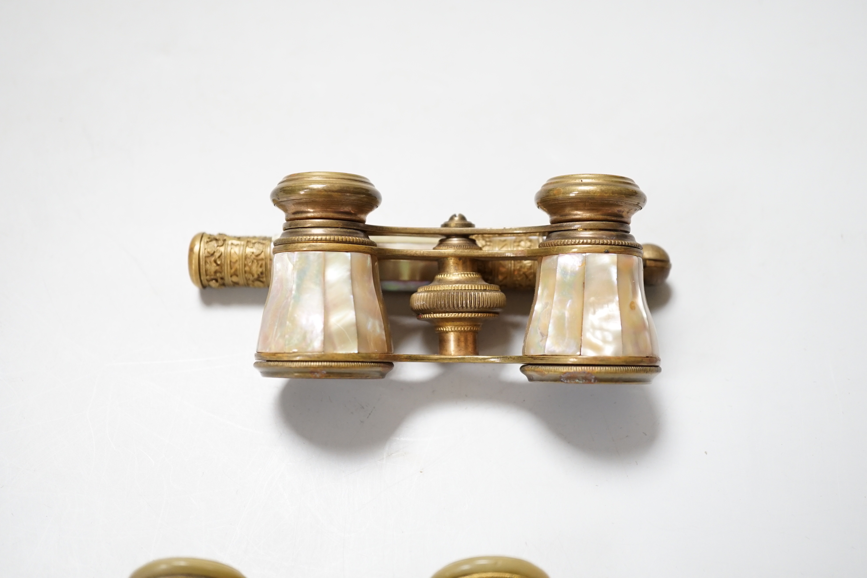 A pair of gilt brass and enamelled opera glasses and a similar pair of mother-of-pearl veneered opera glasses